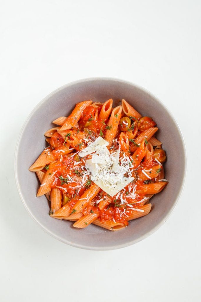 Top view of a white bowl filled with penne pasta in red sauce and cheese. Perfect for food photography.